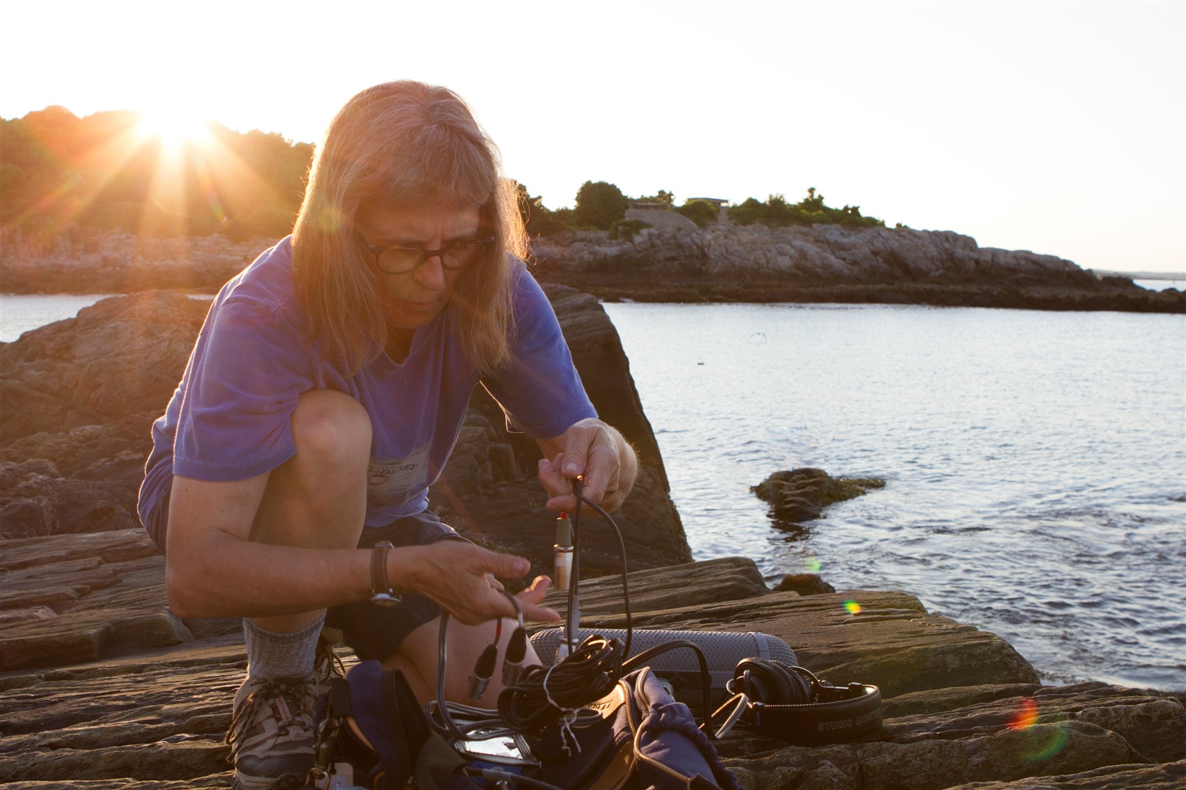 Dianne gathering audio cords on the rocks at sundown